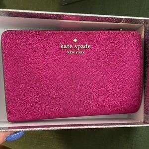 Kate Spade Medium Compact Wallet comes with a glamorous glitter finish